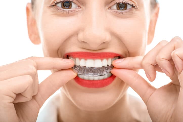 A smiling women holding invisalign