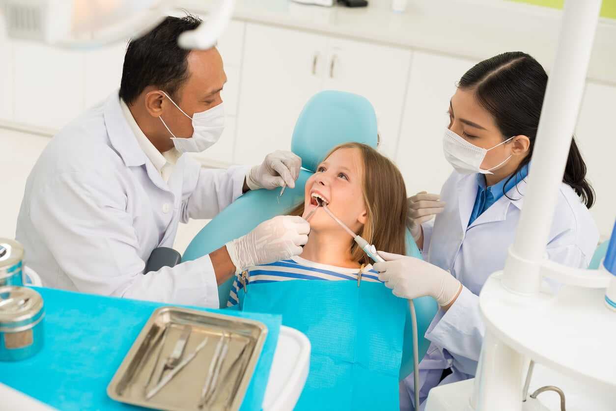 Dentist and Nurse treating the teeth of a girl